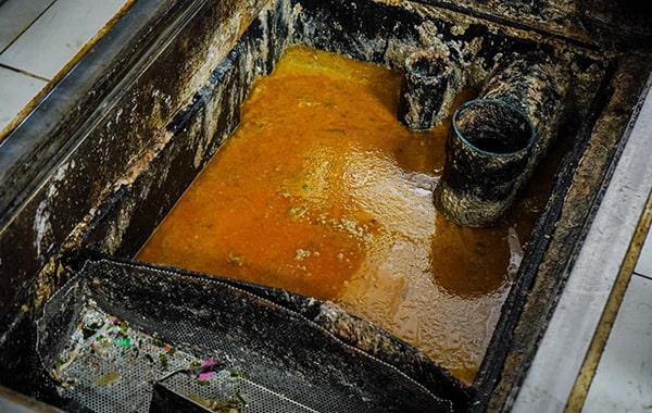 foul odors, slow drainage, and grease buildup in drains are signs that a grease trap requires cleaning